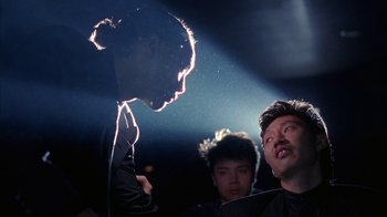 Movie still from “King of New York” (1990), directed by Abel Ferrara – A group of men standing next to each other on a stage; Close Up shot, Over the shoulder angle