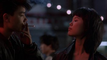 Movie still from “King of New York” (1990), directed by Abel Ferrara – A man and a woman are smoking a cigarette together; Close Up shot, Over the shoulder angle