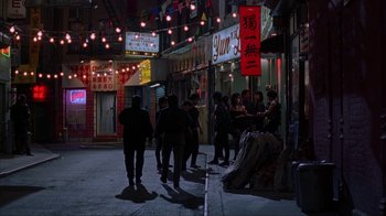 Movie still from “King of New York” (1990), directed by Abel Ferrara – A group of people standing on the sidewalk at night; Wide shot, High angle