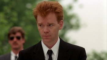 Movie still from “King of New York” (1990), directed by Abel Ferrara – A person wearing a suit and tie; Close Up shot, Over the shoulder angle