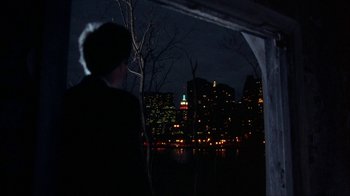 Movie still from “King of New York” (1990), directed by Abel Ferrara – A man looking out over a body of water at night; Wide shot, Over the shoulder angle