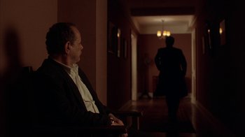 Movie still from “King of New York” (1990), directed by Abel Ferrara – A man sitting in a chair in front of a man in a suit; Wide shot, Over the shoulder angle