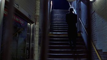 Movie still from “King of New York” (1990), directed by Abel Ferrara – A man walking down a set of stairs at night; Wide shot, Low angle