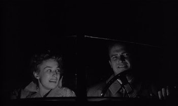 Movie still from “Kiss Me Deadly” (1955), directed by Robert Aldrich – A man and a woman sitting in a car at night; Close Up shot, Low angle