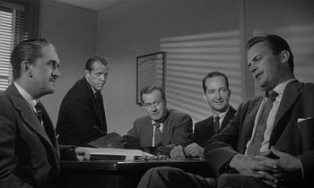 Movie still from “Kiss Me Deadly” (1955), directed by Robert Aldrich – A black and white photo of a group of men sitting at a table; Medium shot, Over the shoulder angle
