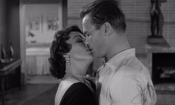 Movie still from “Kiss Me Deadly” (1955), directed by Robert Aldrich – A man and a woman kissing each other in front of a building; Close Up shot, High angle