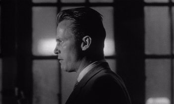 Movie still from “Kiss Me Deadly” (1955), directed by Robert Aldrich – Black and white photograph of a man in a suit and tie; Close Up shot, Low angle