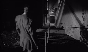 Movie still from “Kiss Me Deadly” (1955), directed by Robert Aldrich – A black and white photo of a man walking down a street; Wide shot, High angle