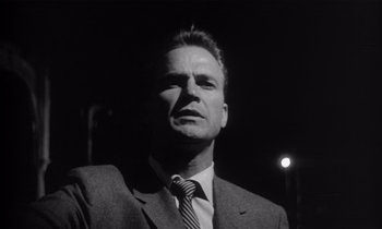 Movie still from “Kiss Me Deadly” (1955), directed by Robert Aldrich – Black and white photograph of a man wearing a suit and tie; Close Up shot, Low angle