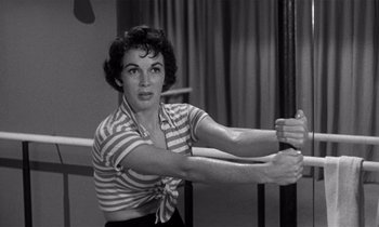 Movie still from “Kiss Me Deadly” (1955), directed by Robert Aldrich – An old photo of a woman doing a dance move; Medium shot, Low angle