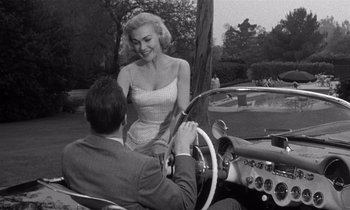 Movie still from “Kiss Me Deadly” (1955), directed by Robert Aldrich – A man and a woman sitting in the driver's seat of a car; Medium shot, Low angle