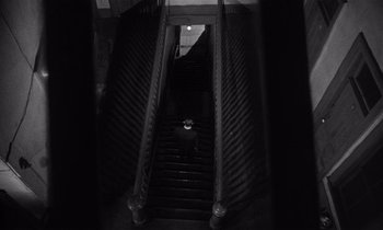 Movie still from “Kiss Me Deadly” (1955), directed by Robert Aldrich – A person walking down a set of stairs; Extreme Wide shot, High angle