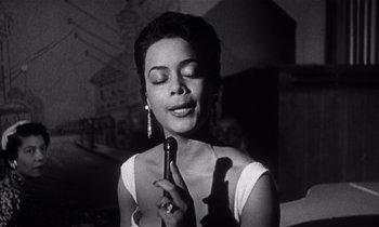 Movie still from “Kiss Me Deadly” (1955), directed by Robert Aldrich – A black and white photo of a woman holding a microphone; Close Up shot, Low angle
