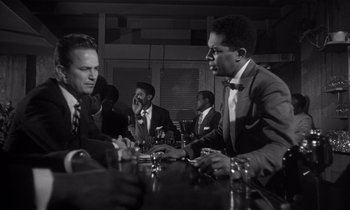 Movie still from “Kiss Me Deadly” (1955), directed by Robert Aldrich – A black and white photo of men sitting at a table; Medium shot, Low angle