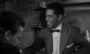 Movie still from “Kiss Me Deadly” (1955), directed by Robert Aldrich – A black and white photo of a man in a suit; Medium shot, Over the shoulder angle