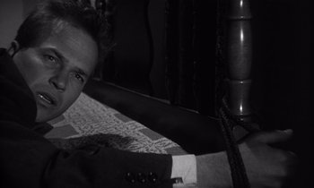 Movie still from “Kiss Me Deadly” (1955), directed by Robert Aldrich – A black and white photo of a man in a suit and tie; Close Up shot, High angle