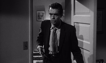 Movie still from “Kiss Me Deadly” (1955), directed by Robert Aldrich – Black and white photograph of a man in a suit and tie holding a gun; Medium shot, Low angle