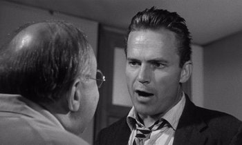 Movie still from “Kiss Me Deadly” (1955), directed by Robert Aldrich – A black and white photo of a man talking to another man; Close Up shot, Over the shoulder angle