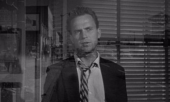 Movie still from “Kiss Me Deadly” (1955), directed by Robert Aldrich – Black and white photograph of a man wearing a suit and tie; Close Up shot, Over the shoulder angle