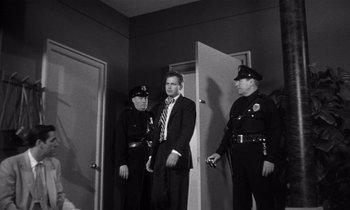Movie still from “Kiss Me Deadly” (1955), directed by Robert Aldrich – Three police officers standing in a room next to each other; Medium shot, Low angle