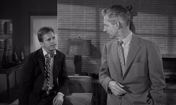 Movie still from “Kiss Me Deadly” (1955), directed by Robert Aldrich – Two men in business suits talking to each other; Medium shot, Over the shoulder angle