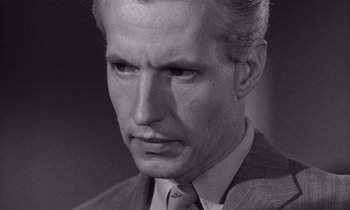 Movie still from “Kiss Me Deadly” (1955), directed by Robert Aldrich – An old photo of a man in a suit and tie; Close Up shot, High angle