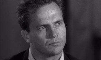 Movie still from “Kiss Me Deadly” (1955), directed by Robert Aldrich – Black and white photograph of a man in a business suit; Close Up shot, Over the shoulder angle