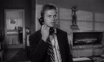 Movie still from “Kiss Me Deadly” (1955), directed by Robert Aldrich – A black and white photo of a man talking on a phone; Medium shot, Low angle