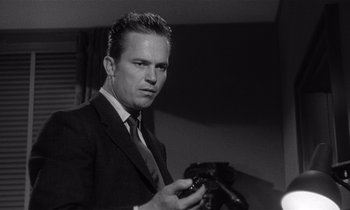 Movie still from “Kiss Me Deadly” (1955), directed by Robert Aldrich – A black and white photo of a man holding a camera; Close Up shot, Low angle