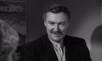 Movie still from “Kiss Me Deadly” (1955), directed by Robert Aldrich – An older man with a mustache wearing a suit and tie; Close Up shot, Low angle