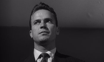 Movie still from “Kiss Me Deadly” (1955), directed by Robert Aldrich – Black and white photograph of a man wearing a suit and tie; Close Up shot, Low angle
