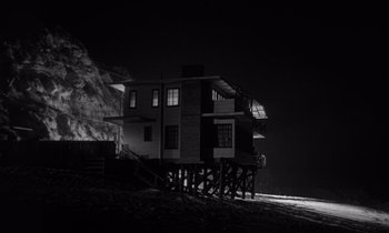 Movie still from “Kiss Me Deadly” (1955), directed by Robert Aldrich – A black - and - white photo of a house at night; Extreme Wide shot, Low angle