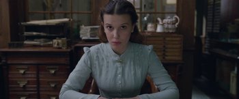 Movie still from “Enola Holmes 2” (2022), directed by Harry Bradbeer – A woman sitting in a chair in a room; Medium shot, Over the shoulder angle
