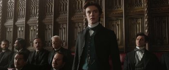 Movie still from “Enola Holmes 2” (2022), directed by Harry Bradbeer – A man in a suit and tie standing next to another man in a suit and tie; Medium shot, Low angle