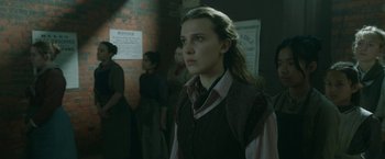 Movie still from “Enola Holmes 2” (2022), directed by Harry Bradbeer – A woman standing in front of a group of people; Medium shot, Over the shoulder angle