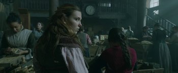 Movie still from “Enola Holmes 2” (2022), directed by Harry Bradbeer – A woman standing in front of other people in a room; Medium shot, Over the shoulder angle