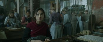 Movie still from “Enola Holmes 2” (2022), directed by Harry Bradbeer – A young girl wearing a red scarf in front of a group of people; Medium shot, Over the shoulder angle