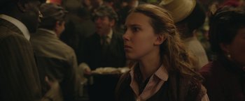 Movie still from “Enola Holmes 2” (2022), directed by Harry Bradbeer – A woman with long blonde hair wearing a brown jacket; Close Up shot, Over the shoulder angle