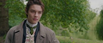 Movie still from “Enola Holmes 2” (2022), directed by Harry Bradbeer – A man in a suit and tie standing in front of a tree; Close Up shot, Over the shoulder angle