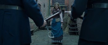 Movie still from “Enola Holmes 2” (2022), directed by Harry Bradbeer – A woman is standing in the middle of a courtyard; Medium shot, Over the shoulder angle