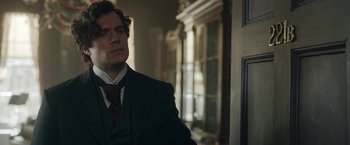 Movie still from “Enola Holmes 2” (2022), directed by Harry Bradbeer – A man wearing a suit and tie standing in front of a door; Close Up shot, Over the shoulder angle