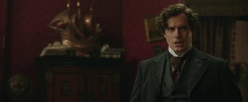 Movie still from “Enola Holmes 2” (2022), directed by Harry Bradbeer – A man wearing a suit and tie in a room; Close Up shot, Over the shoulder angle