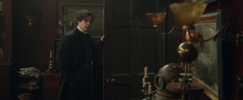 Movie still from “Enola Holmes 2” (2022), directed by Harry Bradbeer – A man standing in front of a door in a room; Medium shot, Over the shoulder angle