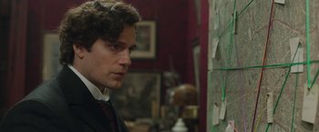 Movie still from “Enola Holmes 2” (2022), directed by Harry Bradbeer – A man in a suit and tie looking to his left; Close Up shot, Over the shoulder angle