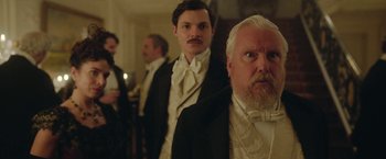 Movie still from “Enola Holmes 2” (2022), directed by Harry Bradbeer – A group of men standing next to each other in tuxedos; Close Up shot, Over the shoulder angle