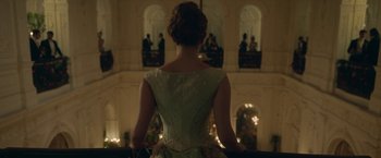 Movie still from “Enola Holmes 2” (2022), directed by Harry Bradbeer – A woman in a green dress standing in front of a building; Medium shot, Over the shoulder angle