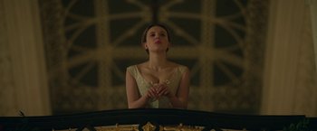 Movie still from “Enola Holmes 2” (2022), directed by Harry Bradbeer – A woman standing in front of a wall with her hands clasped together; Medium shot, Low angle