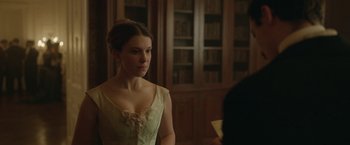 Movie still from “Enola Holmes 2” (2022), directed by Harry Bradbeer – A beautiful young lady wearing a dress in a library; Close Up shot, Over the shoulder angle