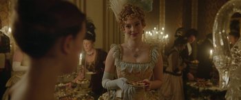 Movie still from “Enola Holmes 2” (2022), directed by Harry Bradbeer – A woman dressed in period clothing holding a plate of food; Medium shot, Over the shoulder angle