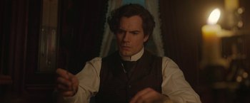 Movie still from “Enola Holmes 2” (2022), directed by Harry Bradbeer – A man in a suit and tie holding a knife; Close Up shot, Over the shoulder angle